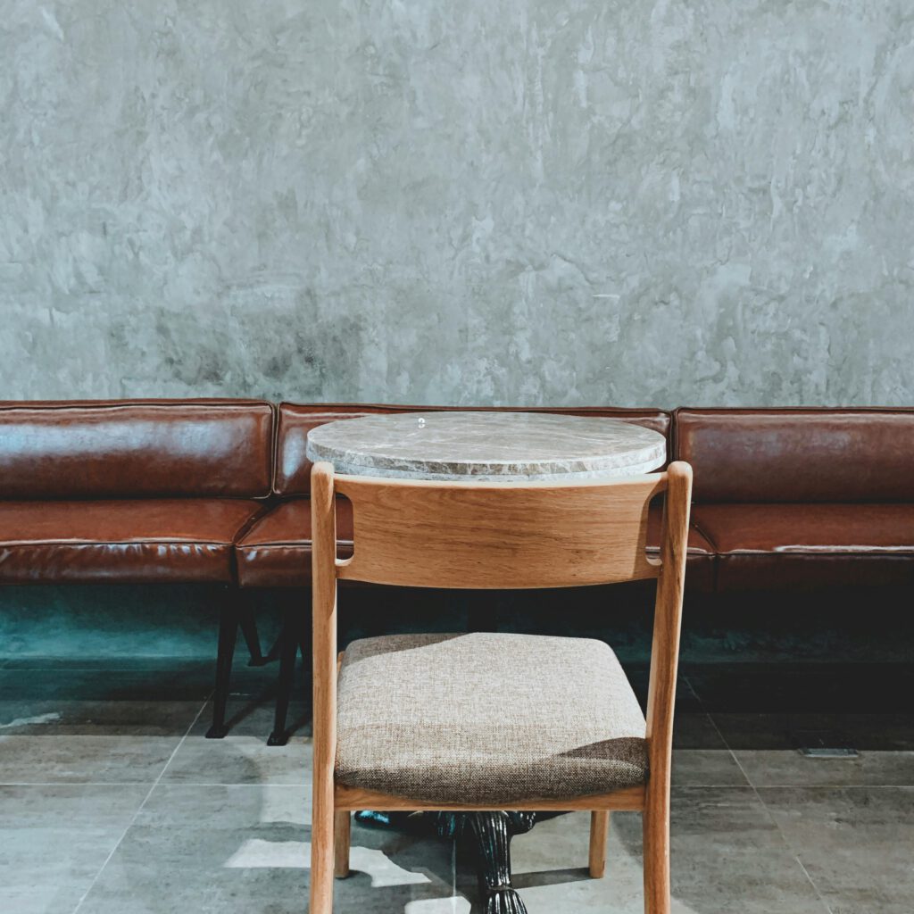 A stylish cafe interior featuring leather benches and wooden chairs against a textured wall.