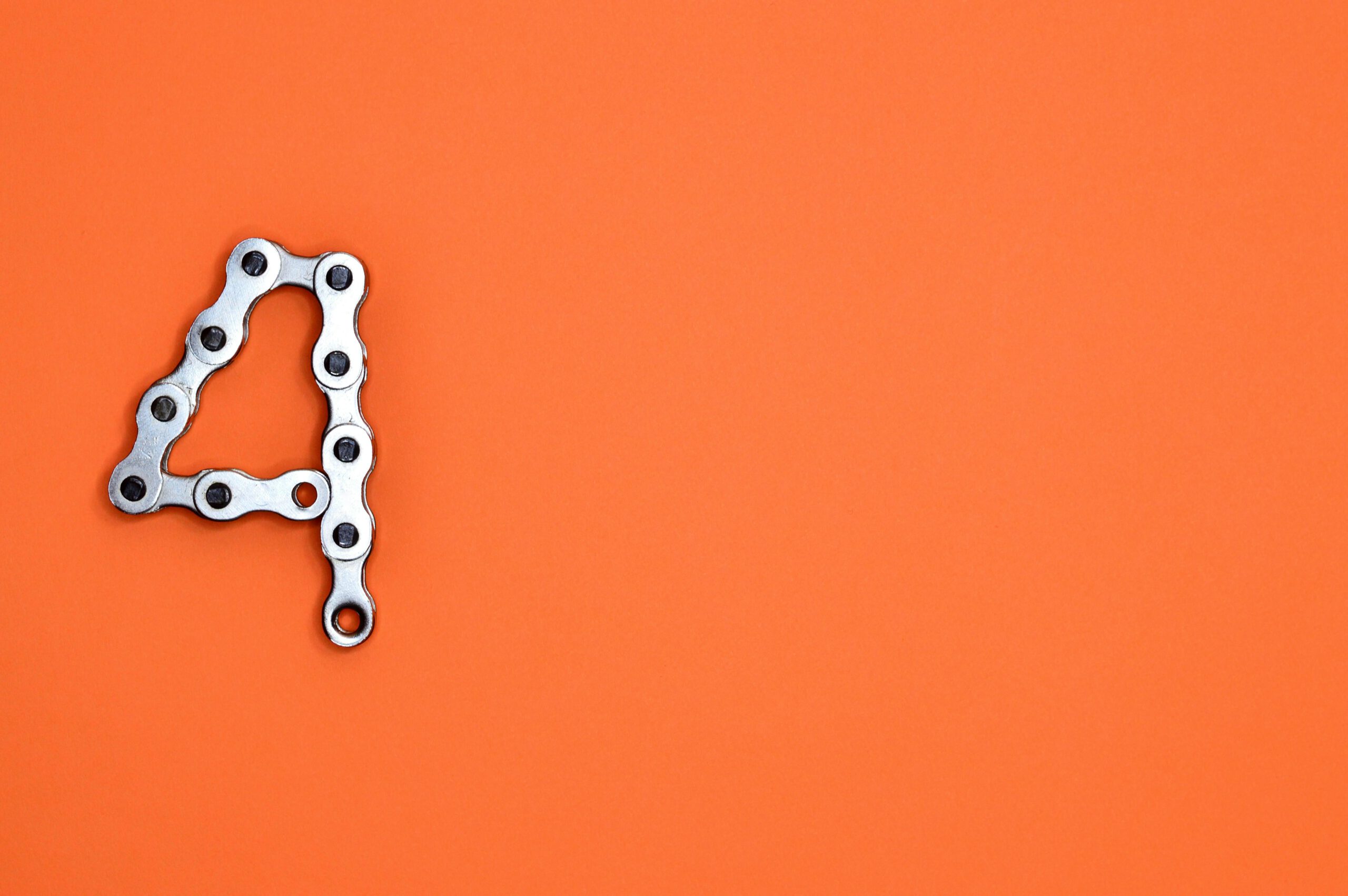 A creative design of the number four formed with a metal chain against an orange background, offering ample copy space.